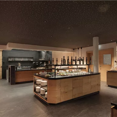 A modern restaurant with wooden and stone elements. Various dishes and drinks are presented on the buffet.
