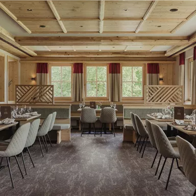 An elegant restaurant with wooden decor and cozy tables. Large windows offer a view outside and provide plenty of light.