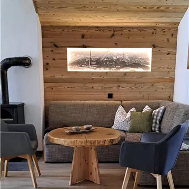 Ein gemütlicher Wohnbereich mit modernen Möbeln und einer Holzverkleidung. Der runde Tisch aus Holz ergänzt die entspannte Atmosphäre.