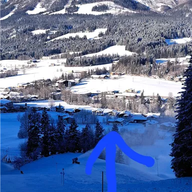 A winter landscape with snow-covered mountains and a quiet valley. The sky is clear and blue.