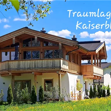 A modern building in a picturesque landscape overlooking the mountains. Surrounded by green meadows and blue sky.