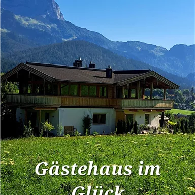 A charming guesthouse in a green setting with a magnificent view of the mountains. The sky is clear and the landscape invites relaxation.