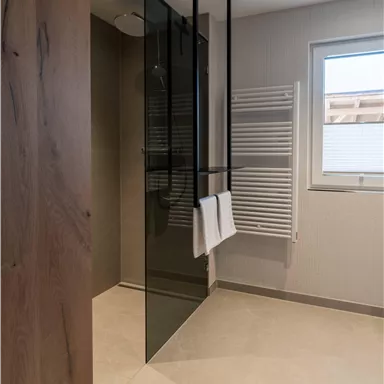 Ein modernes Badezimmer mit einer gläsernen Dusche und einem Handtuchhalter. Der Raum ist hell und elegant gestaltet.