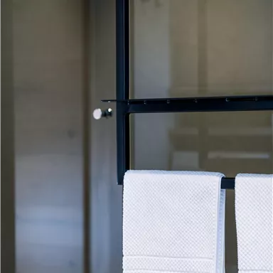 Ein modernes Badezimmer mit zwei weißen Handtüchern, die an einem Halter hängen. Die Wolken- und Glasoptik sorgt für eine elegante Atmosphäre.