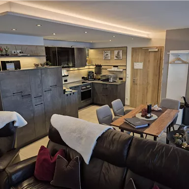 A modern and cozy kitchen with a dining area and comfortable seating area. The decor is in neutral colors and conveys an inviting atmosphere.