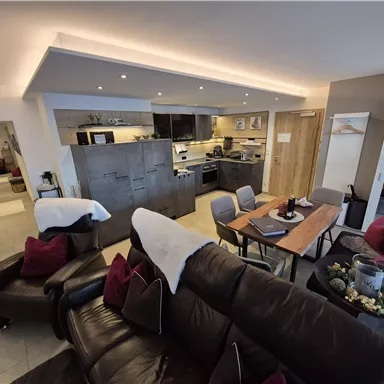 A modern apartment with an open kitchen and a cozy living area. The dining area is set up in an inviting space with comfortable furniture.