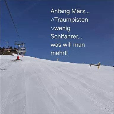 A picturesque ski slope in spring with perfect snow and clear blue sky. Only a few skiers are enjoying the dreamy slopes.