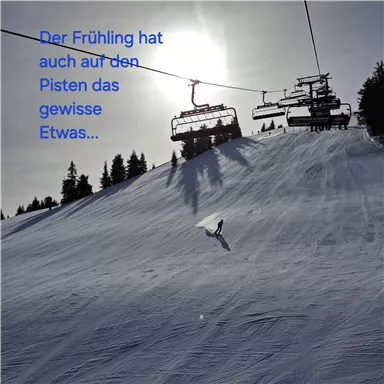 A snow-covered slope in spring with a female skier. In the background, ski lifts and a clear sky can be seen.