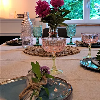 A beautifully set table with elegant plates, glassware, and fresh flowers. The atmosphere is inviting and friendly.