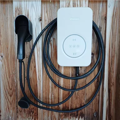 A control device with a long cable and an earphone rests on a wooden surface. The buttons on the device are for controlling the audio functionality.