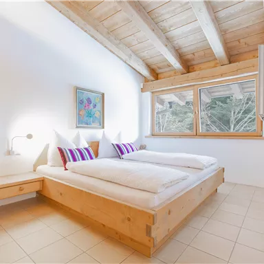 A cozy bedroom with wooden decor and large windows.
Two beds with white bedding and colorful pillows invite you to relax.
