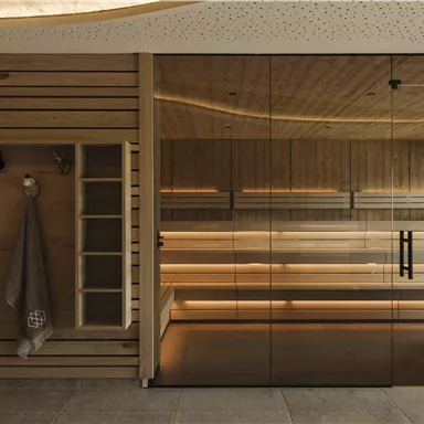 Ein modernes Zimmer mit Holzwänden und einer Glaswand. Die sanfte Beleuchtung schafft eine entspannte Atmosphäre.