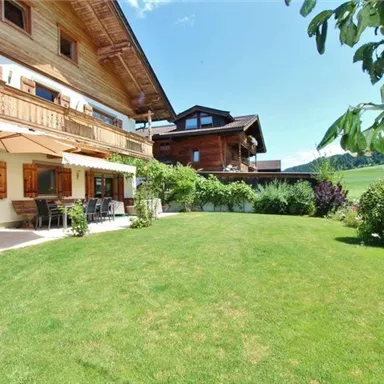 Ein schönes Haus mit einer großen Wiese und gepflegtem Garten. Die Umgebung ist grün und sonnig, ideal für entspannte Tage im Freien.