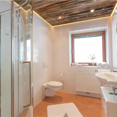 Ein modernes Badezimmer mit einer Duschkabine und einem Waschbecken. Helle Wände und ein Holzdecke schaffen eine einladende Atmosphäre.