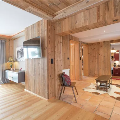 Ein gemütlicher Innenraum mit Holzverkleidung und einem offenen Wohnbereich. Im Hintergrund ist eine moderne Küche zu sehen.
