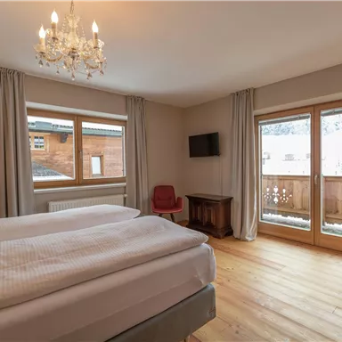 Ein gemütliches Schlafzimmer mit einem Doppelbett und großen Fenstern. Der Raum ist hell und modern eingerichtet, mit Zugang zu einem Balkon.