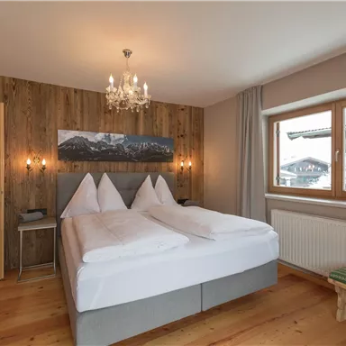 Ein gemütliches Doppelzimmer mit Holzvertäfelung und einem großen Fenster. Die Atmosphäre ist warm und einladend, ideal für Entspannung.
