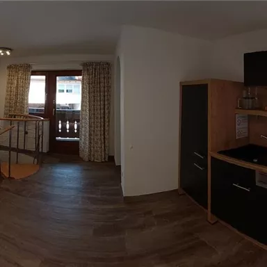 A cozy living room with a modern kitchen and a dining table. The decor is bright and inviting, with wood and neutral tones.
