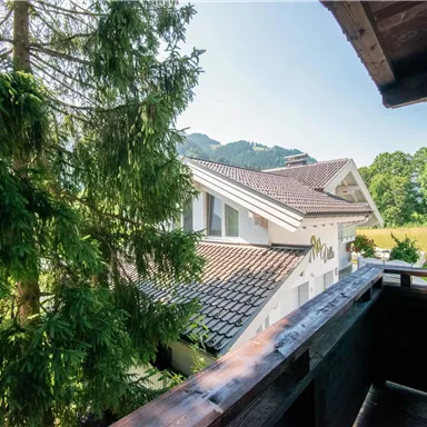 Ein Blick auf ein modernes Haus mit einem geräumigen Balkon. Umgeben von Bäumen und einer grünen Landschaft.