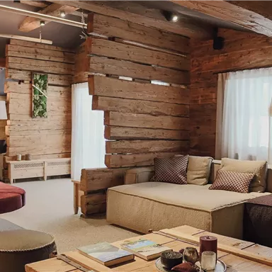 A modern living area with wooden paneling and comfortable sofas. Large windows let in plenty of light and give the room an inviting atmosphere.