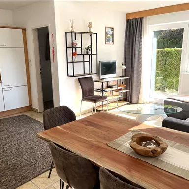 A bright, inviting apartment with an open kitchen and dining area. The living area is modern and cozy with a large window front.