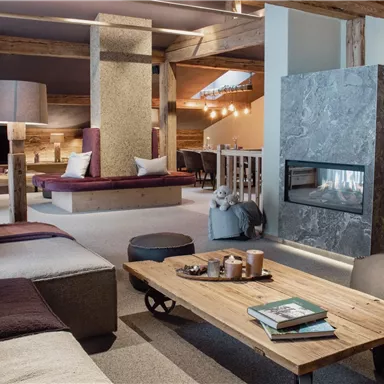 A modern living room with a cozy seating area and a fireplace. The wooden elements and warm colors create an inviting atmosphere.
