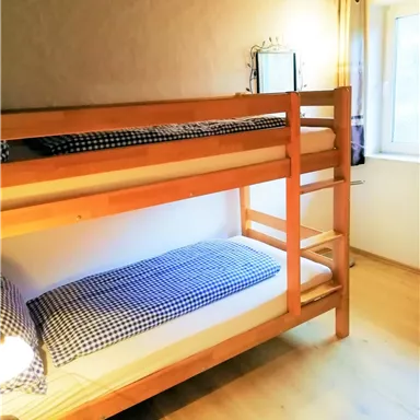 Ein einfaches Schlafzimmer mit einem Etagenbett. Es gibt eine Fenster, das natürliches Licht hereinlässt.