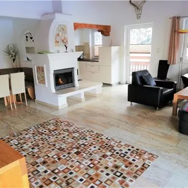 Ein modernes Wohnzimmer mit einem bequemen Sofa und einem Esstisch. Der Kamin sorgt für eine gemütliche Atmosphäre.