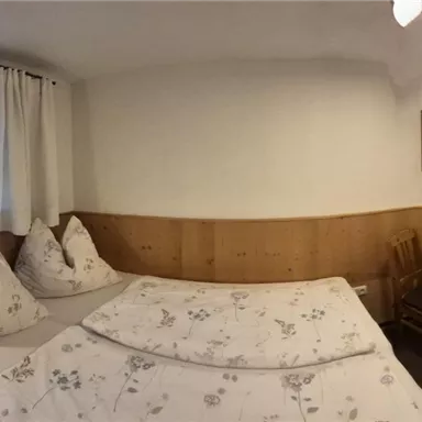 A cozy bedroom with two beds and a small table.  
Bright walls and wooden panels create an inviting atmosphere.