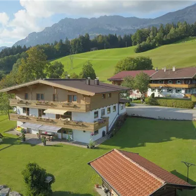 Ein malerisches Landhaus umgeben von grünen Wiesen und Bergen. Die Anlage bietet einen schönen Garten mit Spielplatz und Blick auf die Natur.