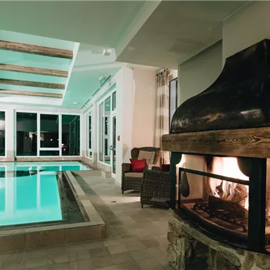 A modern interior with a pool and a cozy fireplace. Large windows let in plenty of light and provide a relaxing atmosphere.