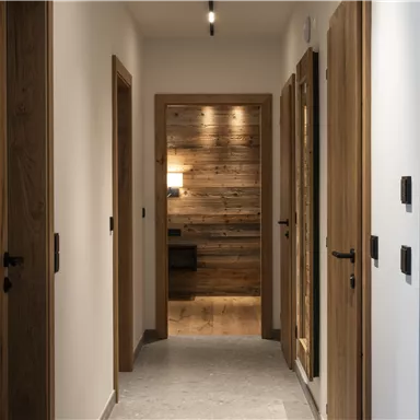 A modern corridor with wooden and white walls. Doors on both sides lead to different rooms.