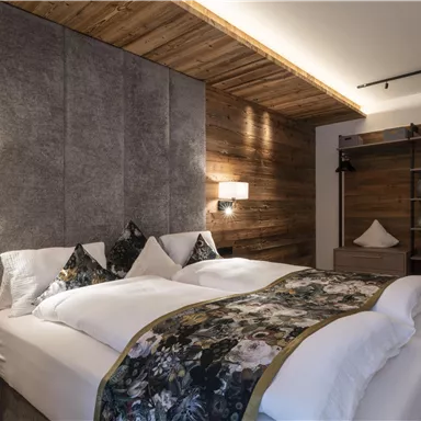 A modern bedroom with a large double bed and cozy wood paneling. The decorative pillows and soft lighting create an inviting atmosphere.
