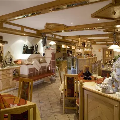 A cozy restaurant with wooden decorations and warm light. The tables are neatly set, and a bar is visible in the background.