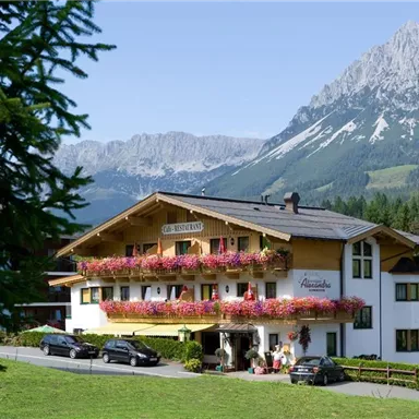 A charming hotel with blooming balconies in the midst of a mountainous landscape. Surrounded by green meadows and majestic mountains.