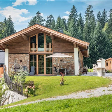 Das Chalet Riederhäusl umgeben von Bäumen und Wiesen. Der große Garten lädt zum Entspannen ein.