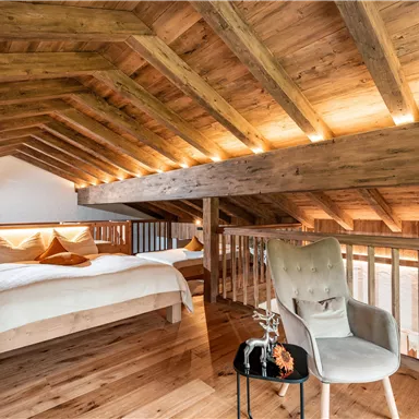 Der nach oben offene Schlafboden mit einem Holzfußboden und einer modernen Holzdecke. Ein bequemes Bett und ein Stuhl mit einem kleinen Tisch schaffen eine einladende Atmosphäre.