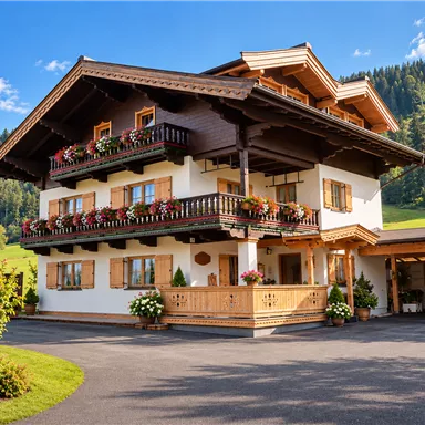 Ein charmantes, zweigeschossiges Haus mit Holzverkleidung und Blumenkästen. Umgeben von grünen Wiesen und Bergen, strahlt es eine einladende Atmosphäre aus.