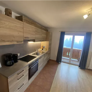 Eine moderne Küche mit Holzschränken und Küchenzeile. Sie bietet einen Zugang zu einem Balkon mit Aussicht.