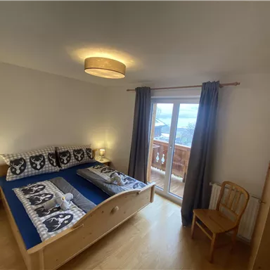 Ein gemütliches Schlafzimmer mit zwei Betten und modernen Bettwäsche. Die große Fensterfront bietet einen schönen Blick nach draußen.