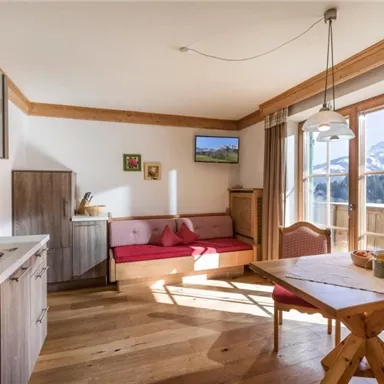 A cozy kitchen with a dining table and seating area. Large windows provide a view of the mountains and let in plenty of light.