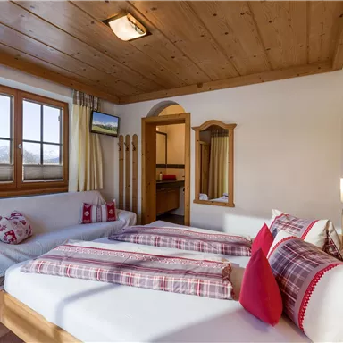 A cozy bedroom with two beds and wooden elements. The room features large windows with a beautiful view and is designed in warm colors.