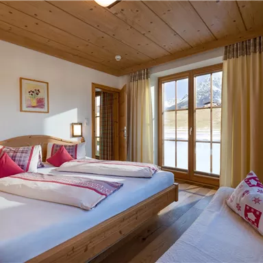 A cozy bedroom with two beds and wooden furniture.
Large windows provide plenty of daylight and offer a view outside.