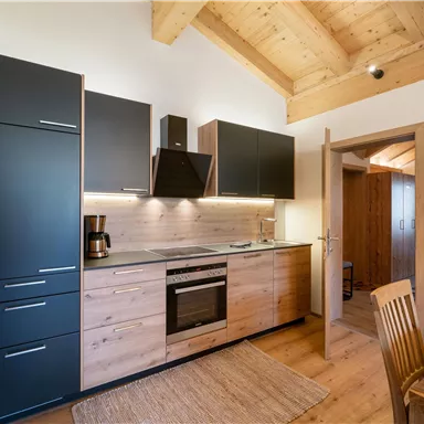 A modern kitchen with wood and black elements. It is bright and inviting, with an open layout.