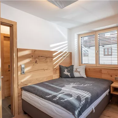A cozy bedroom with wooden paneling and a large bed. The room has plenty of natural light and a modern, inviting atmosphere.