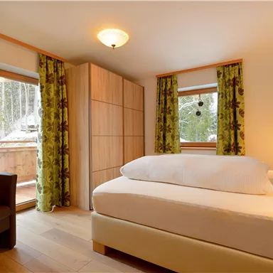 A cozy bedroom with a large bed and a beautiful view of nature. The green curtains create a vibrant atmosphere.