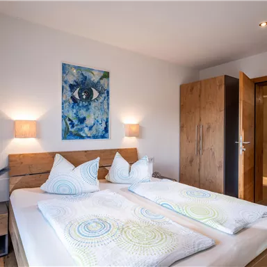Ein modernes Schlafzimmer mit einem Doppelbett und zwei Nachttischen. An der Wand hängt ein Gemälde, und es gibt einen Zugang zum Badezimmer.