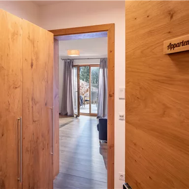 Ein einladender Flur mit Holzpaneelen, der zu einem gemütlichen Appartement führt. Auf einem Schild steht "Appartement Hans".