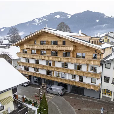 A modern wooden building in alpine style, surrounded by snow. The mountains are visible in the background.