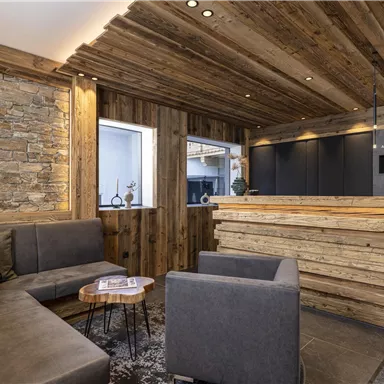 A modern reception hall with wooden paneling and cozy seating areas. The reception desk is made of solid wood and creates an inviting atmosphere.